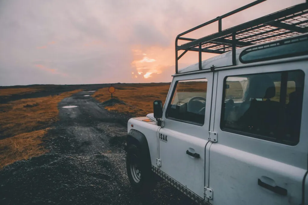 Een witte terreinwagen met roimper staat op een onverharde weg tijdens een roadtrip door de fjorden nabij Egilsstaðir in IJsland.