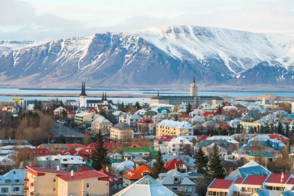 Uitzicht over de kleurrijke daken van Reykjavik met op de achtergrond de met sneeuw bedekte berg Esja in IJsland.