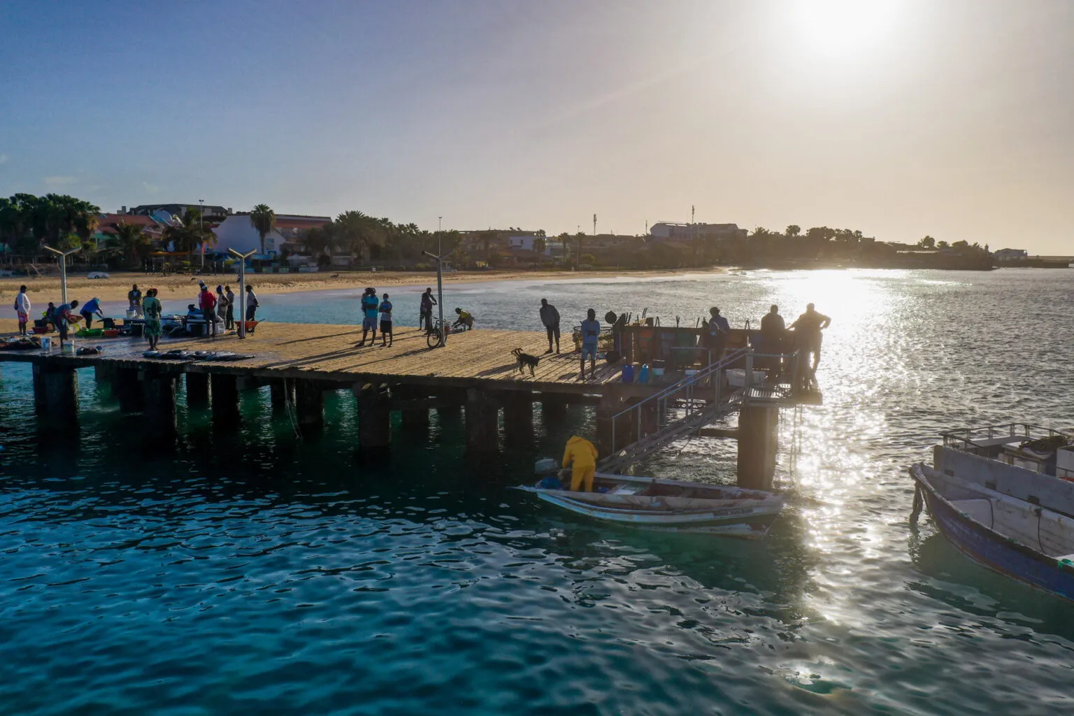 Houten pier van Santa Maria met mensen en vissersbootjes in het heldere zeewater op het eiland Sal, Kaapverdië