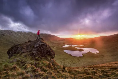 Een reiziger geniet bij zonsondergang van het uitzicht op het landschap van de vulkanische krater Corvo Caldeirao op het eiland Corvo