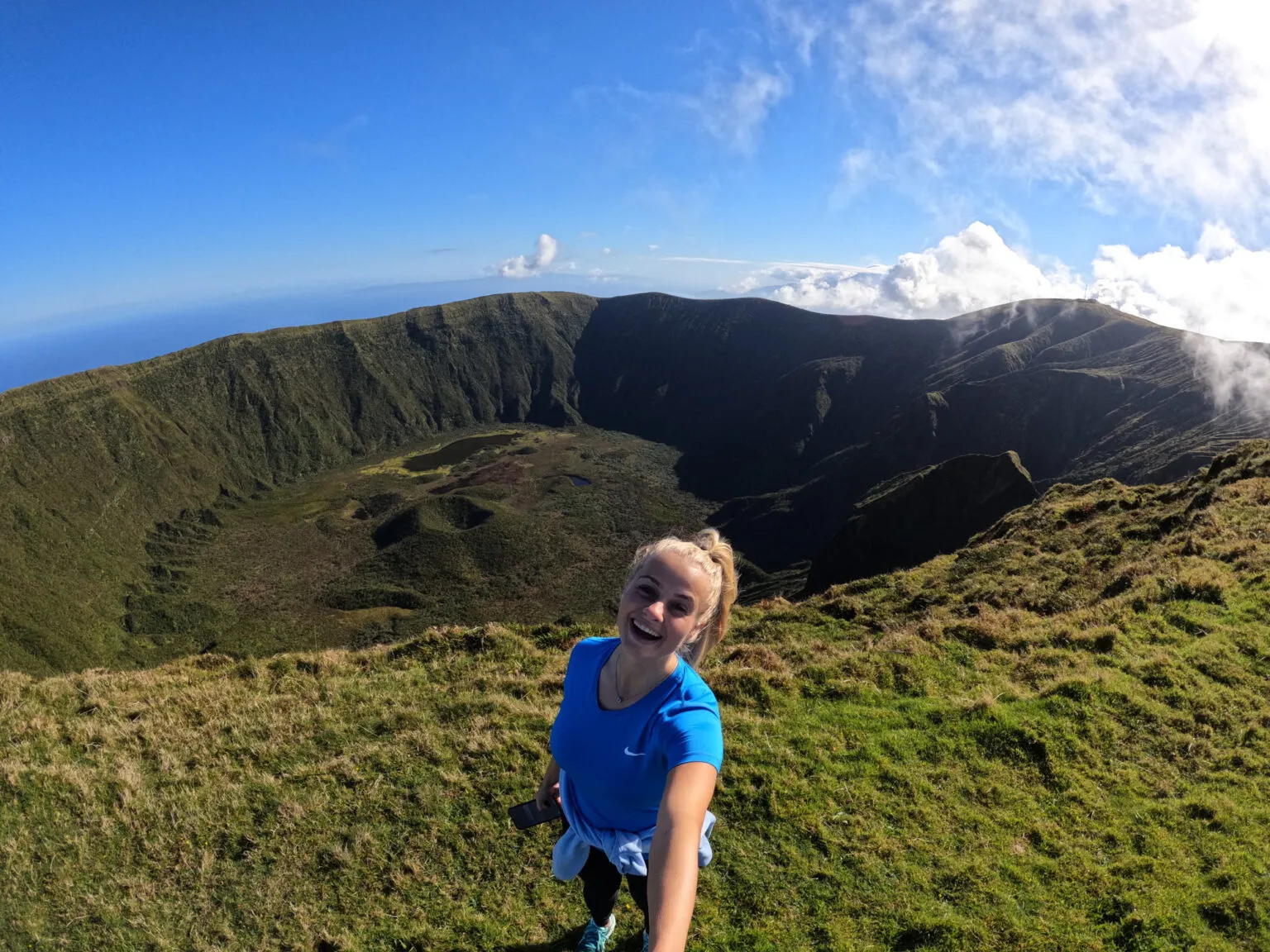 Vrouw maakt een selfie op de rand van de diepe groene Caldeira-krater op het eiland Faial in de Azoren