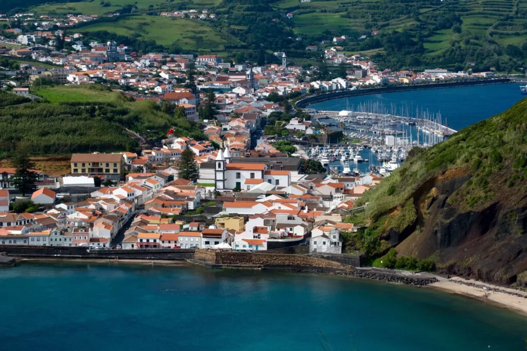 Panoramisch overzicht van de kuststad Horta met witte huizen, een drukke jachthaven en groene heuvels op het eiland Faial in de Azoren