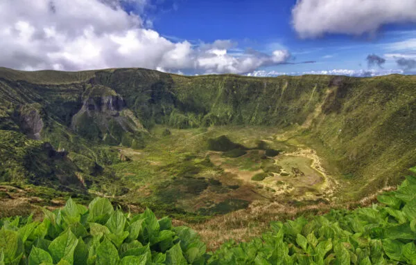 Panoramisch zicht op de diepe, weelderig groene vulkaankrater Caldeira do Faial onder een lichtbewolkte blauwe lucht op het eiland Faial in de Azoren.
