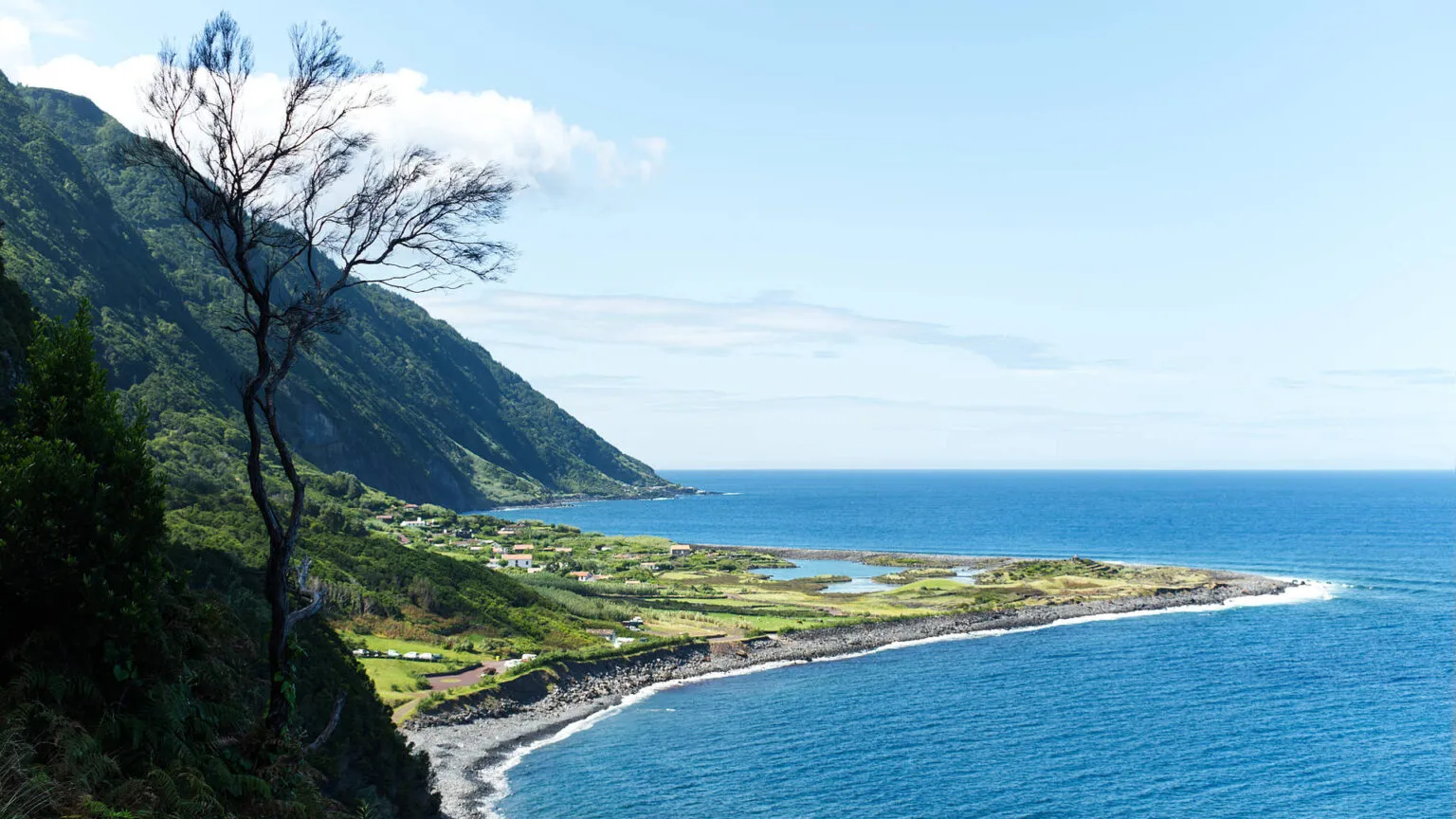 Uitkijk op de groene kustvlakte Fajá de Santo Cristo met een binnenmeer, gelegen aan de voet van steile kliffen aan de oceaan op São Jorge.