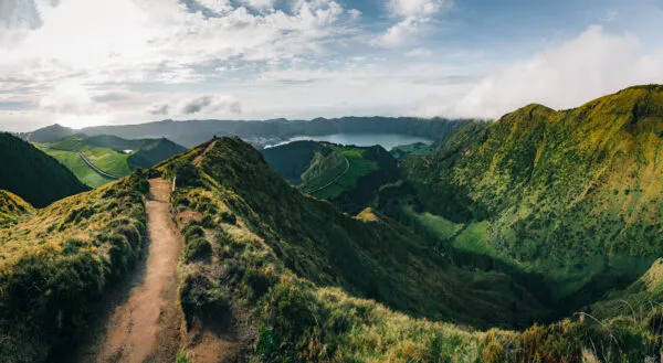 Zandpad kronkelt over een groene bergkam richting een diepe vallei en kratermeer bij Boca do Inferno op het eiland São Miguel in de Azoren