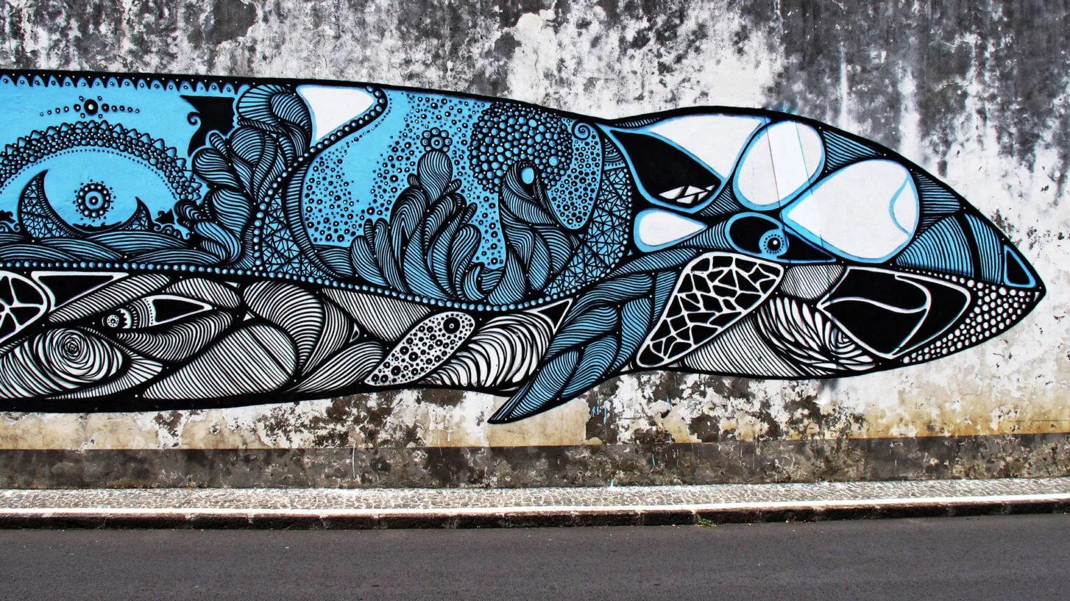 Een kleurrijke muurschildering van een blauw-zwarte walvis op een stenen muur in een straat van Ponta Delgada.