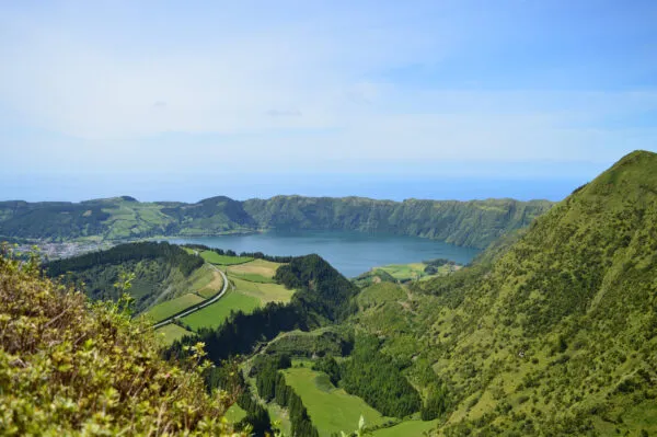 Weids zicht vanaf een hoge berghelling op de groene kraterwanden, velden en het grote meer van Sete Cidades op het eiland São Miguel.