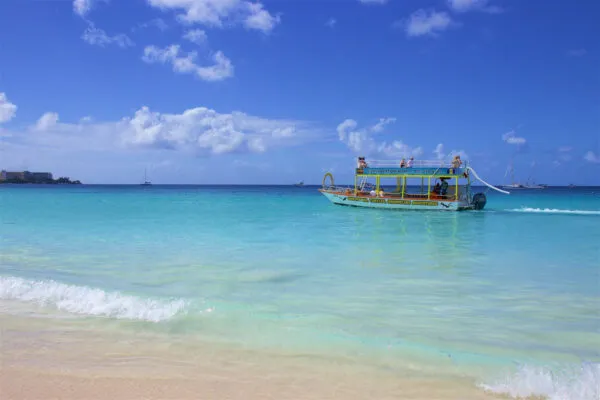 Kleine catamaran voor snorkeluitcursies voor anker op helder turquoise water vlak voor een zandstrand in het zuiden van Barbados.