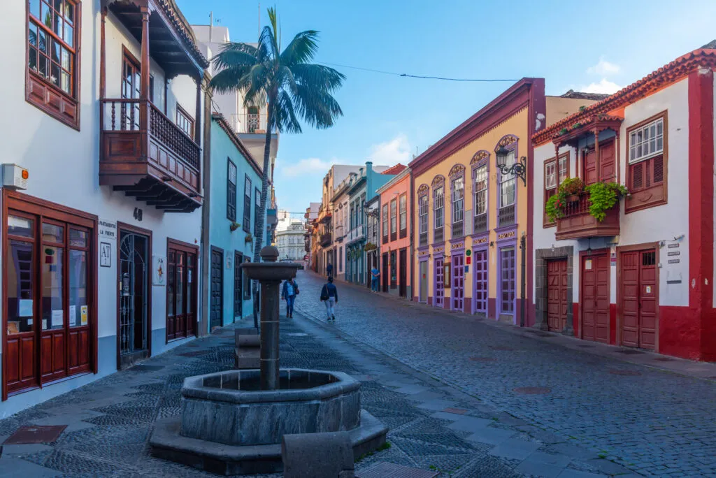 Een rustige, gekasseide straat in Santa Cruz de La Palma met een klassieke fontein, palmbomen en kleurrijke koloniale gevels.