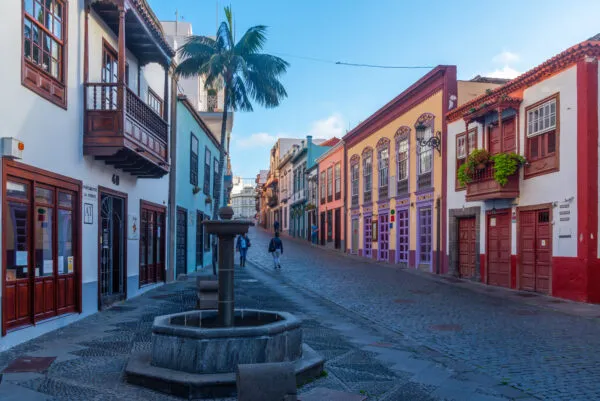 Een rustige, gekasseide straat in Santa Cruz de La Palma met een klassieke fontein, palmbomen en kleurrijke koloniale gevels.
