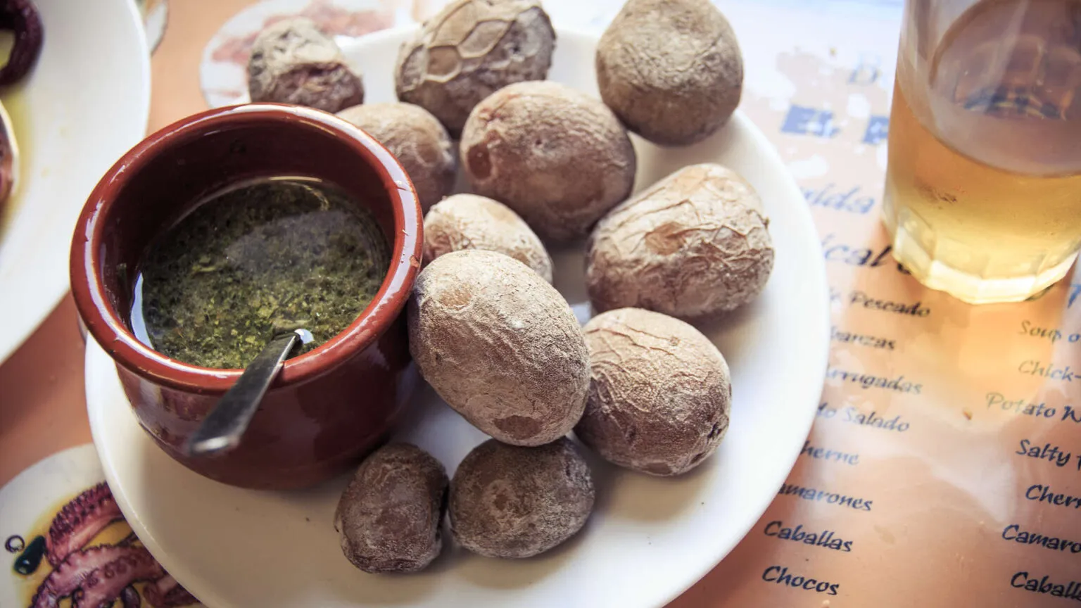 Een bord met traditionele Canarische rimpelaardappels (papas arrugadas) geserveerd met een schaaltje groene mojo-saus op La Gomera.