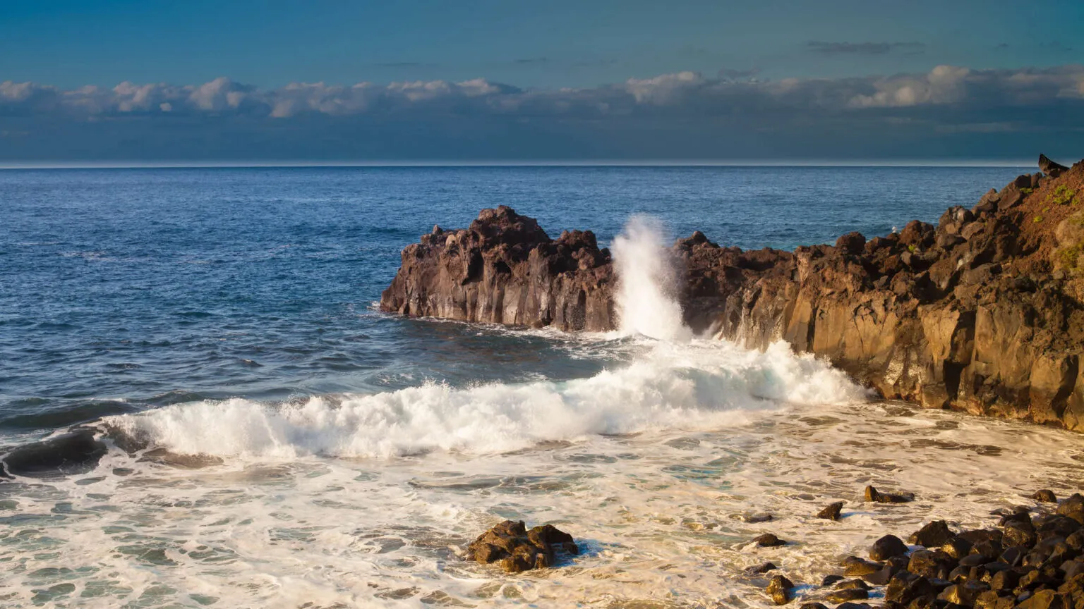 Krachtige golven van de Atlantische Oceaan spattend uiteen tegen ruige rotsformaties op het strand van Playa El Bollullo op Tenerife.