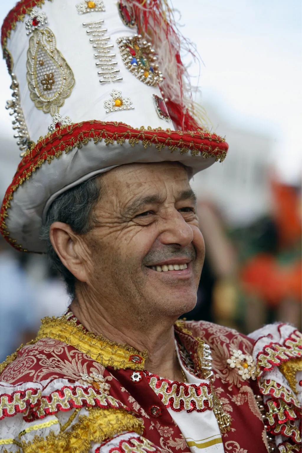 Portret van een lachende man met een versierde carnavalshoed en kleurrijke feestkleding tijdens het carnaval op Tenerife.
