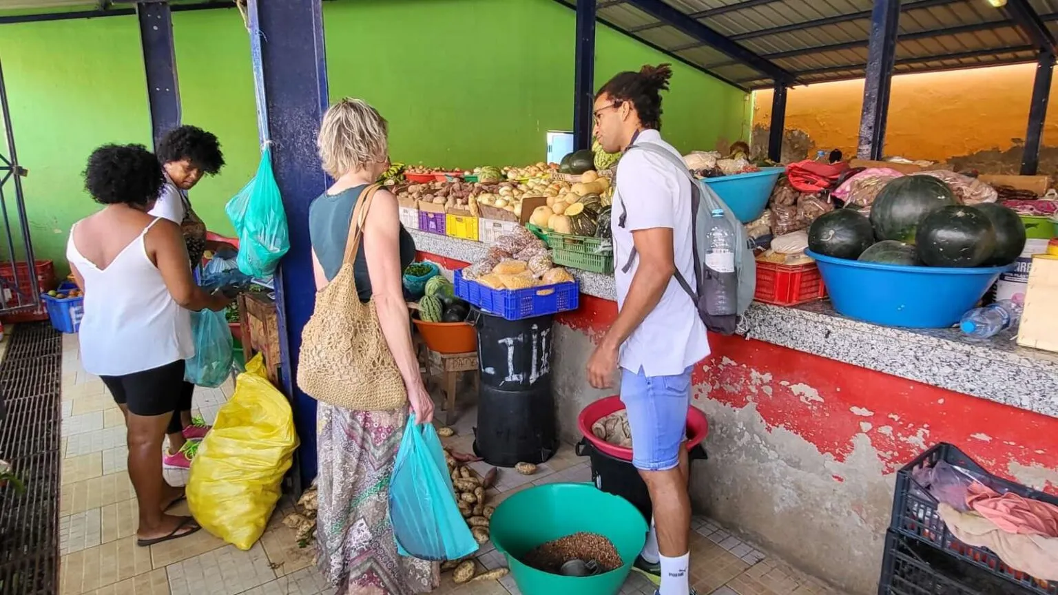 Twee personen bekijken verse groenten en fruit bij een marktkraam tijdens een lokale kookworkshop in Kaapverdië.