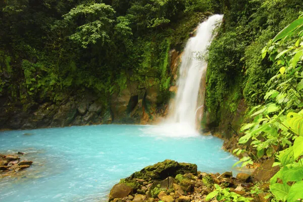 Een waterval spettert neer in turquoise water in de jungle van Costa Rica