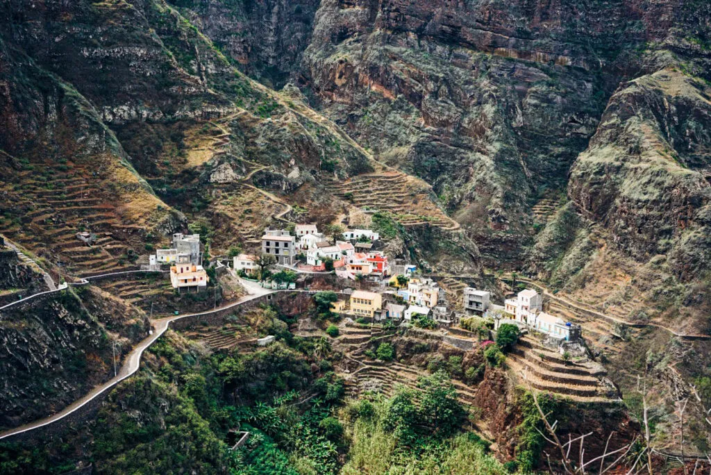 Een cluster van witte en gekleurde huisjes genesteld op steile berghellingen met aangelegde landbouwterrassen op het eiland Santo Antao