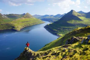 Een reiziger kijkt uit op het Funningur Fjord op het eiland Eysturoy, Faeröer eilanden