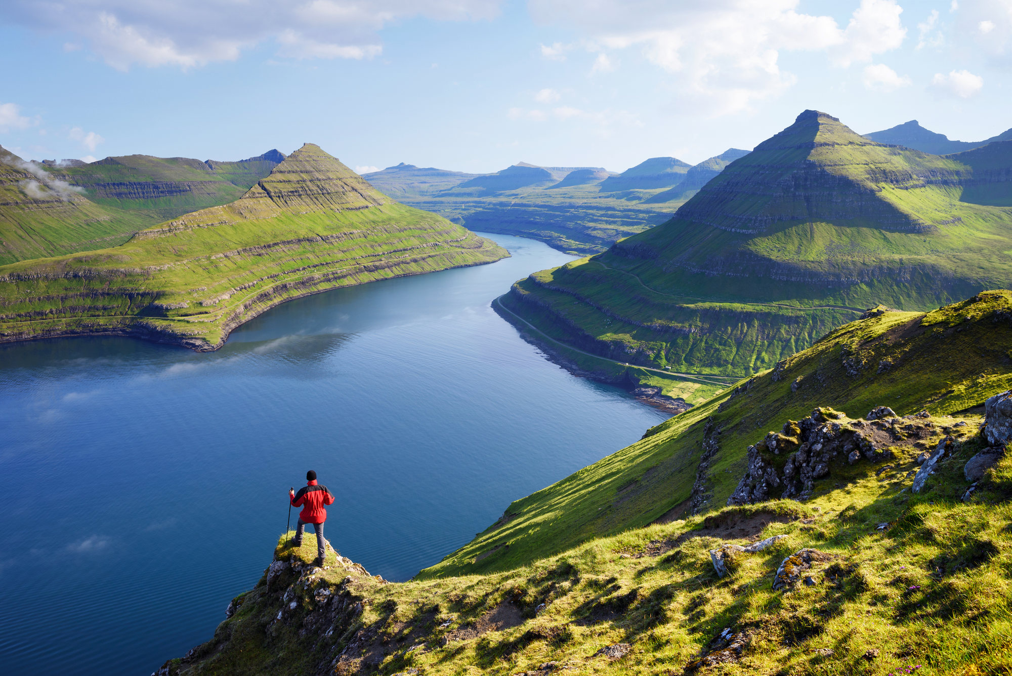 Een reiziger kijkt uit op het Funningur Fjord op het eiland Eysturoy, Faeröer eilanden
