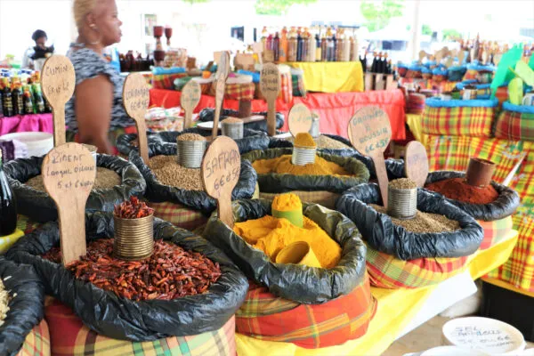 Een overzicht van een marktstalletje op Grande-Terre, Guadeloupe, gevuld met zakken diverse kleurrijke specerijen voorzien van handgeschreven naambordjes.