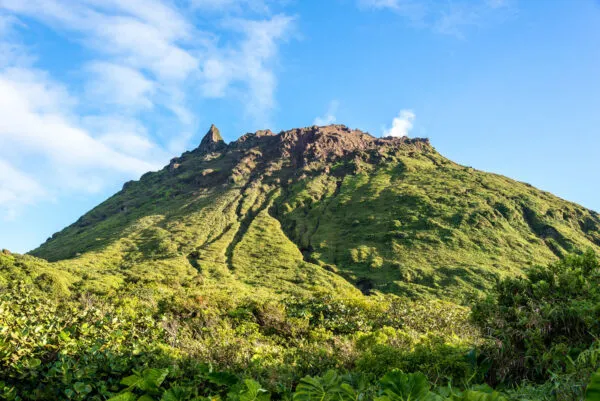 Zicht op de groene, steile hellingen en de rotsachtige top van de actieve vulkaan La Grande Soufrière tegen een heldere blauwe lucht in het zuiden van Basse-Terre op Guadeloupe.