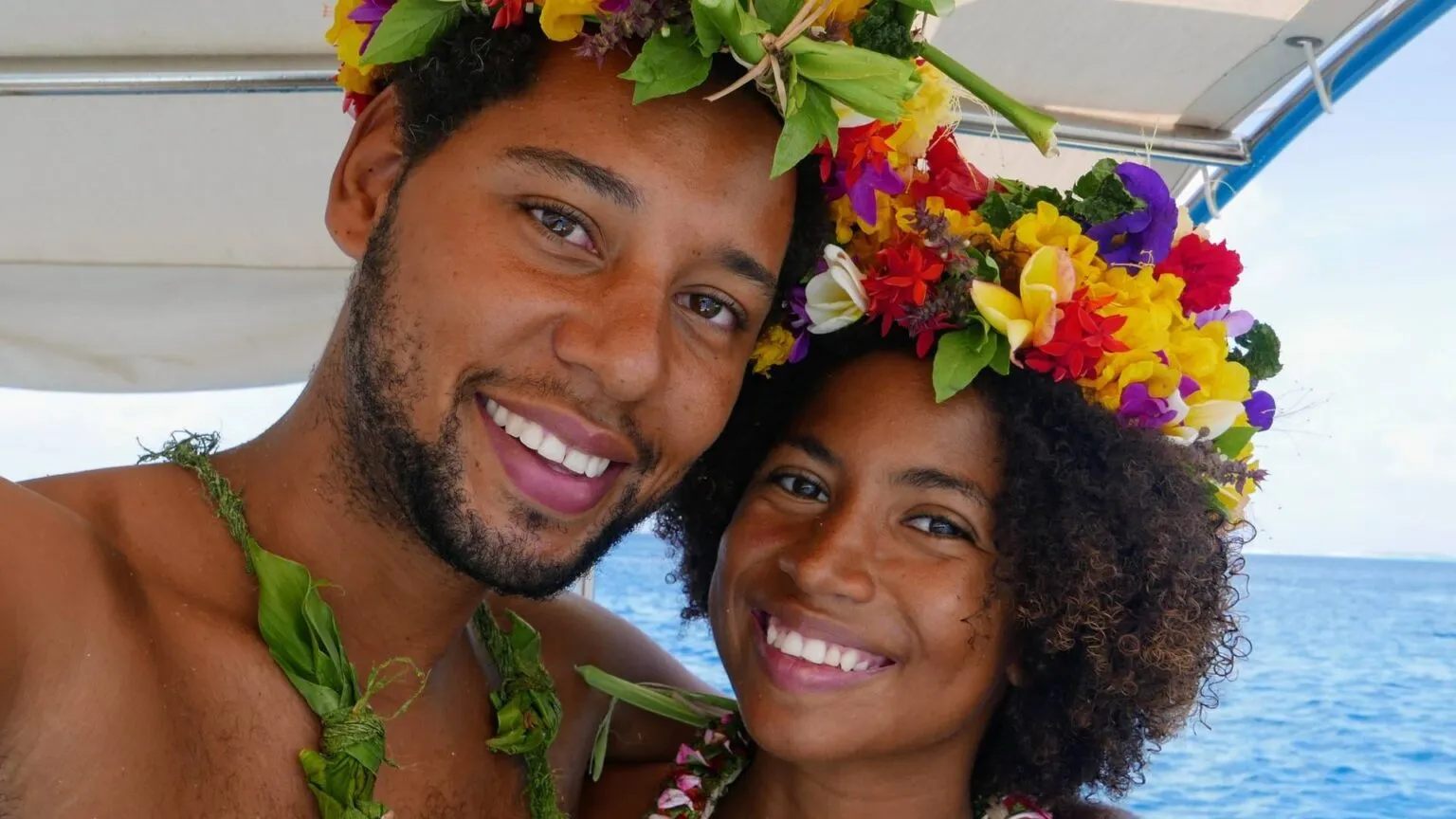 Joshua van Eijndhoven, oprichter van Voja Travel, glimlachend samen met een vrouw terwijl beiden een traditionele kleurrijke bloemenkrans dragen.