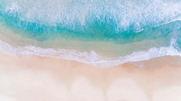 Bovenaanzicht van heldere turquoise golven die omslaan op een wit zandstrand op Boa Vista, Kaapverdië.