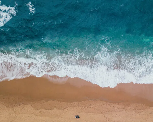 Lucht- en bovenaanzicht van witteschuimende oceaangolven die aanspoelen op het goudgele strand van Boa Vista in Kaapverdië.