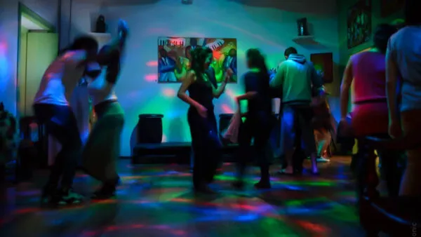 Dansende mensen op een houten dansvloer verlicht met kleurrijke discolichten in een sfeervolle club in Kaapverdië