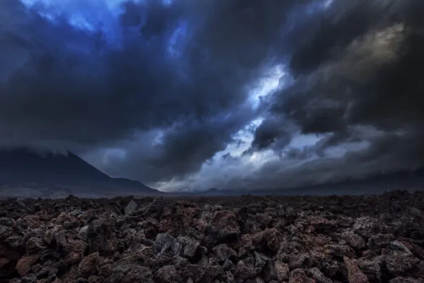 Donkere, dreigende stormwolken hangen boven een ruig veld van vulkanische rotsen op het eiland Fogo, Kaapverdië.