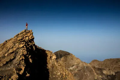Een reiziger staat op de top van de vulkaan Fogo en geniet van het weidse uitzicht