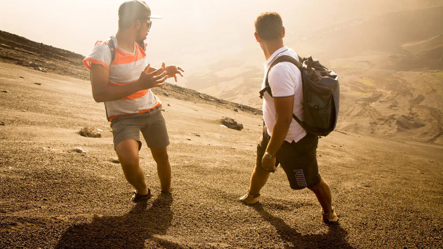 Twee wandelaars met rugzakken wandelen over het zanderige vulkaanlandschap op Fogo in Kaapverdië.