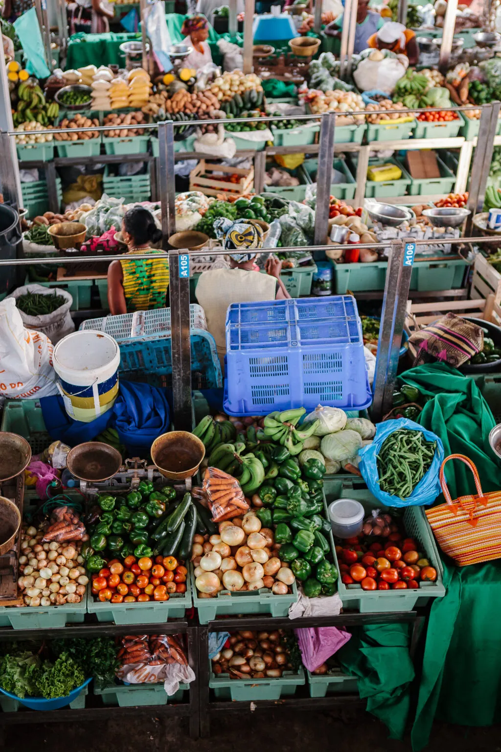 Uitstallingen op een overdekte markt gevuld met diverse kratten vol verse groenten, fruit en specerijen.