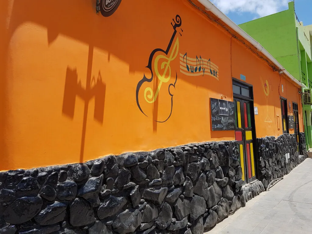 De oranje gevel van de Buddy Bar met het silhouet van een gitaar in Santa Maria op het eiland Sal, Kaapverdië.