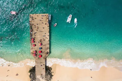 Bovenaanzicht van een houten pier en een vissersbootje in zee bij het strand van Santa Maria op het eiland Sal