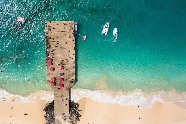 Bovenaanzicht van een houten pier en een vissersbootje in zee bij het strand van Santa Maria op het eiland Sal
