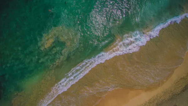 Bovenaanzicht van turquoise zeegolven die omslaan op het goudgele zandstrand van het eiland Sal in Kaapverdië.