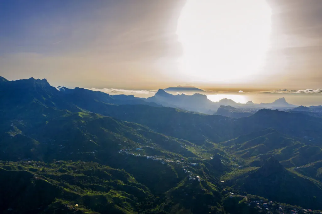 Een panoramisch uitzicht over de bergachtige valleien van Santiago in Kaapverdië tijdens de zonsopkomst, met goud licht dat over de pieken schijnt.