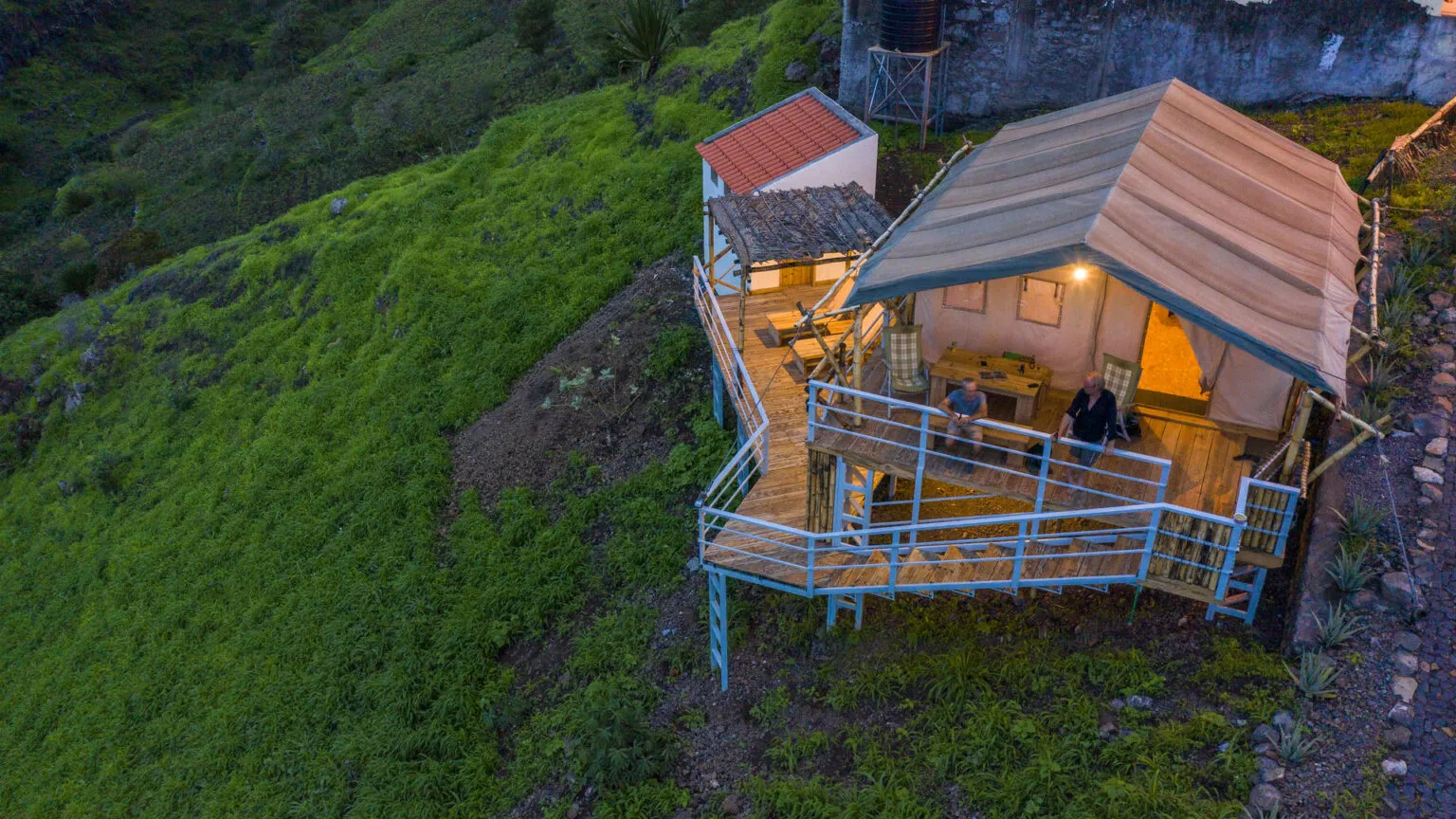 Een sfeervol verlichte eco-lodge met een houten terras, gelegen op de groene bergshellingen van Santiago in Kaapverdië.