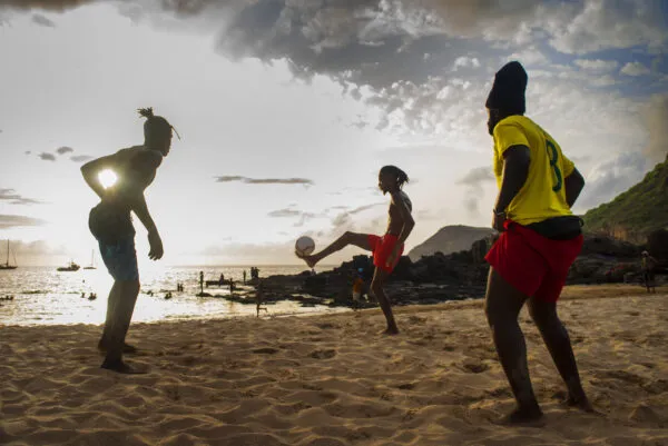 Silhouetten van jongeren die voetballen op een zandstrand bij zonsondergang op het eiland Santiago, Kaapverdië.