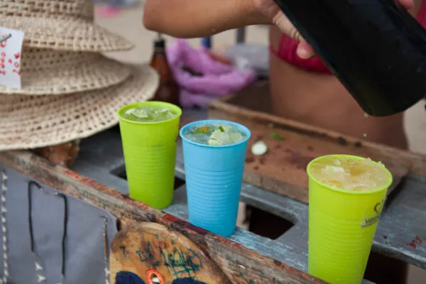 Kleurrijke bekers met verfrissende cocktails met ijs en limoen worden ingeschonken bij een strandbar op Kaapverdië.