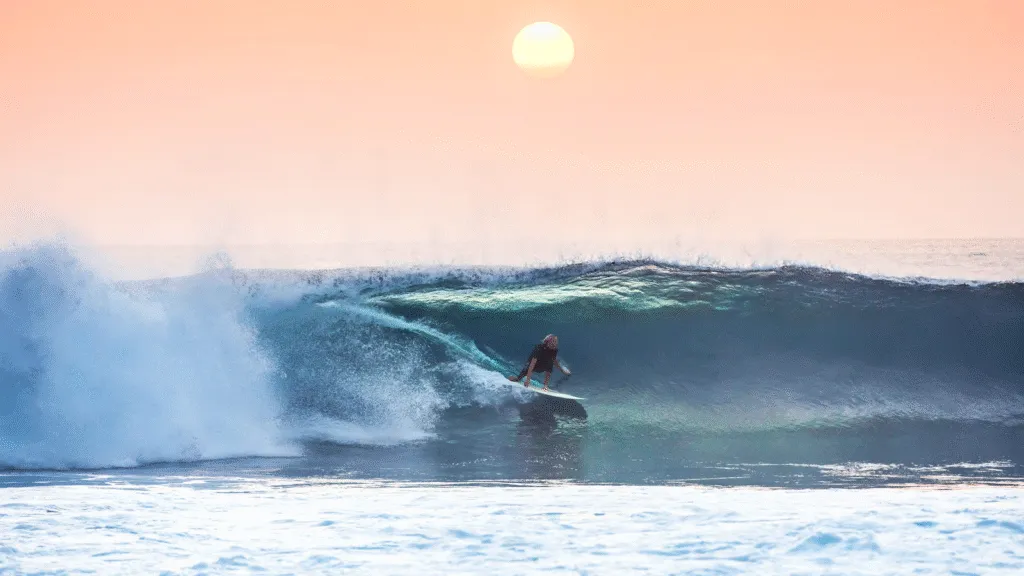 Surfer in de golven tijdens zonsondergang in Tarrafal