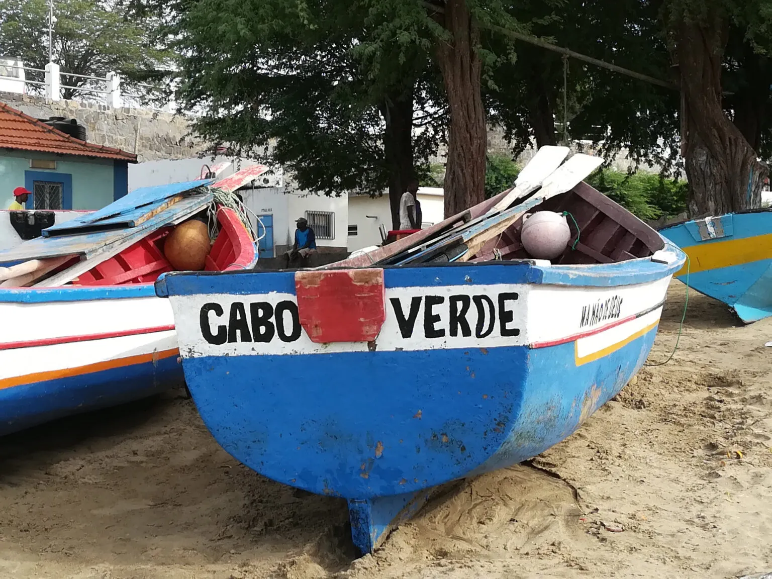Een kleurrijke blauw-witte houten vissersboot met de opdruk Cabo Verde op het zandstrand van Santiago, Kaapverdië.