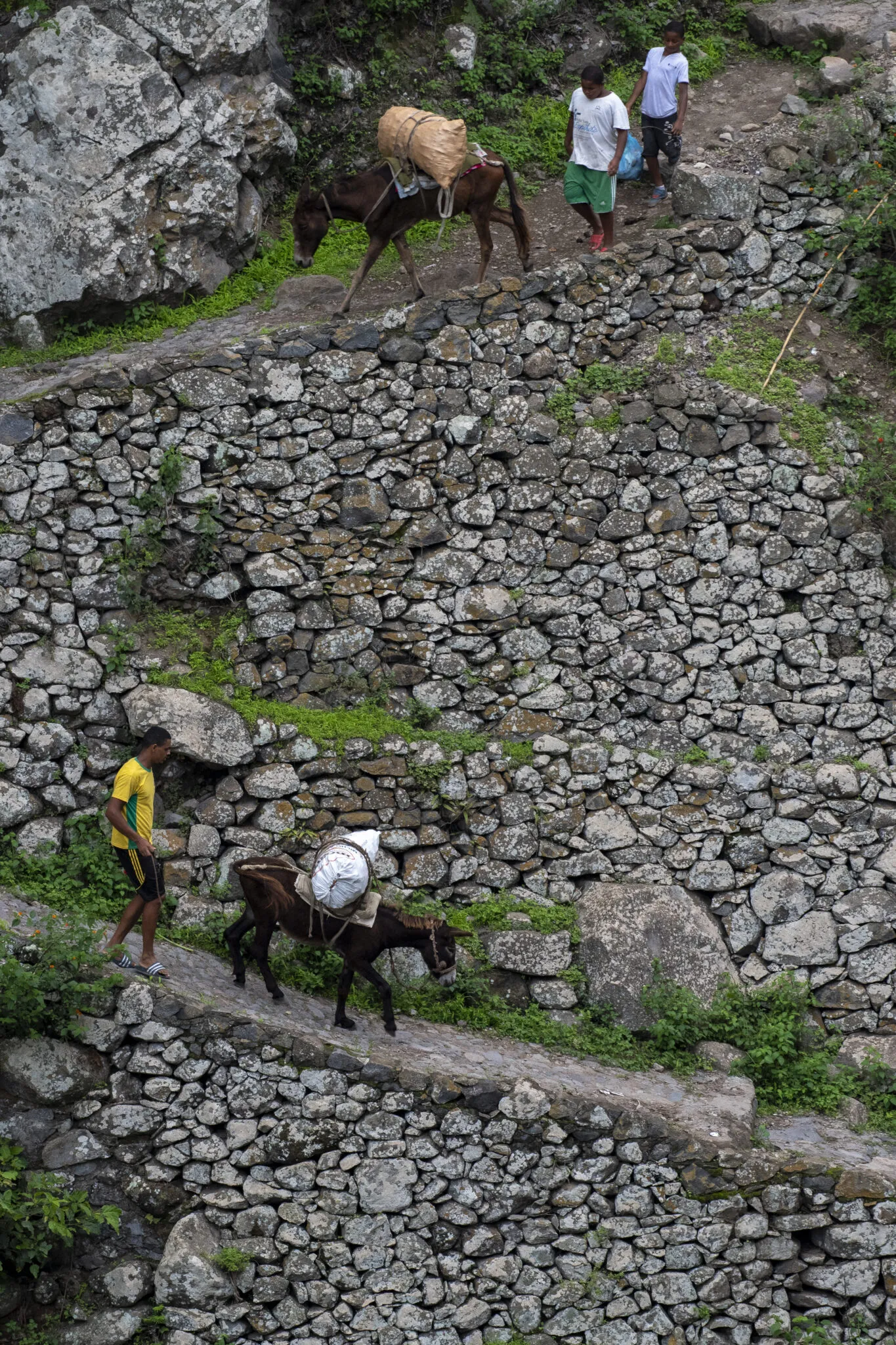 Locals en pakezels lopen smalle bergweggetjes af in het binnenland van het eiland Santo Antão