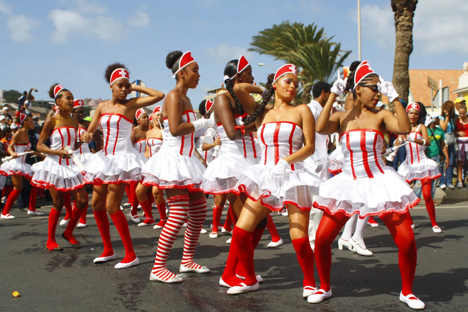 Groep danseressen in rood-wit gestreepte kostuums en rode kousen treedt op tijdens de carnavalsparade op straat op het eiland São Vicente in Kaapverdië