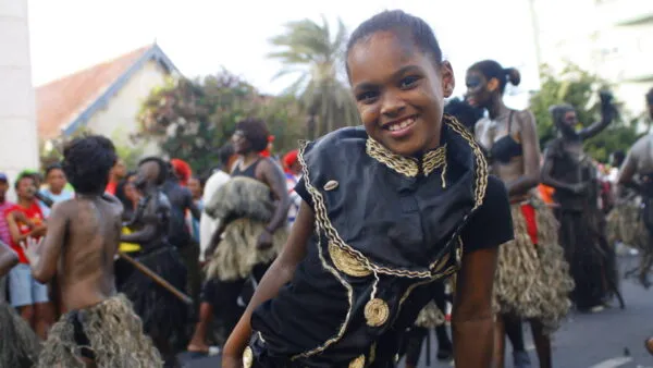 Een glimlachend jong meisje in een donker carnavalskostuum poseert voor de camera tijdens het straatcarnaval op het eiland São Vicente, Kaapverdië.