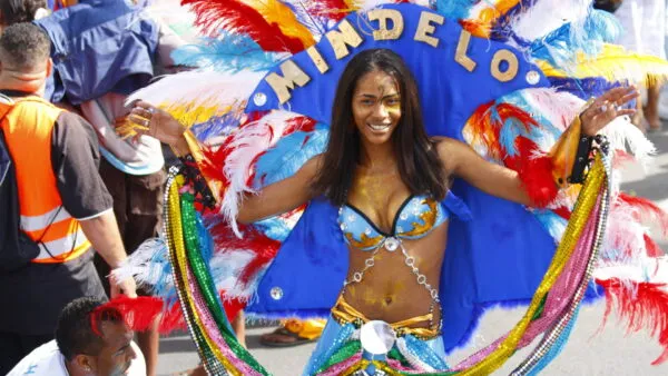 Een vrouw in een kleurrijk carnavalscostuum met een hoofdtooi met de tekst Mindelo danst tijdens het carnaval op São Vicente in Kaapverdië.
