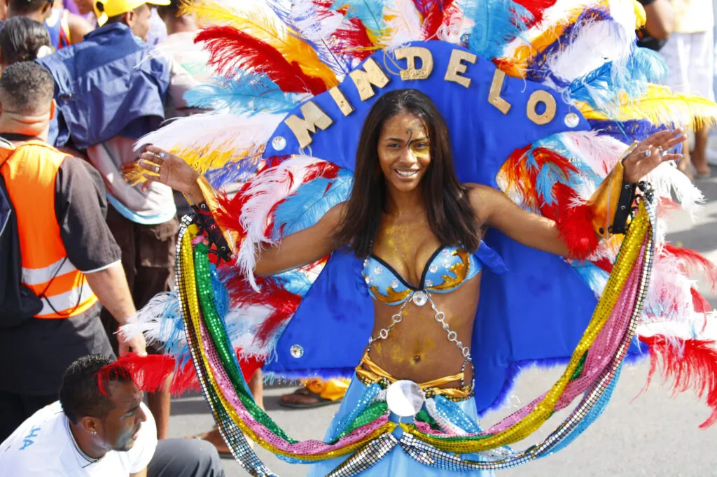 Een dansende vrouw in blauw kostuum en met grote hoofdtooi tijdens het Carnaval in Mindelo, de hoofdstad van São Vicente