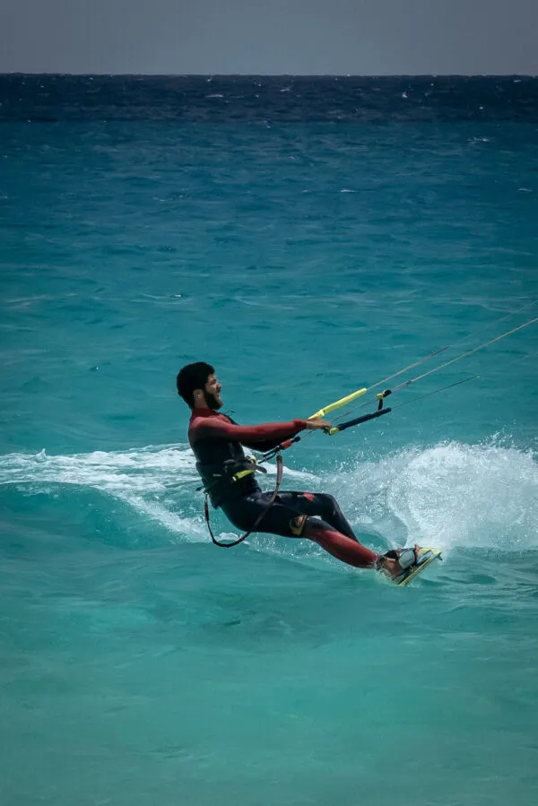 Een man is aan het kitesurfen op een helderblauwe oceaan met spattend water bij São Vicente, Kaapverdië.