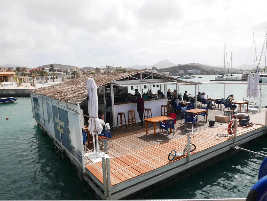 Een houten drijvend terras op het water met zitjes bij de haven van Mindelo op São Vicente, Kaapverdië.