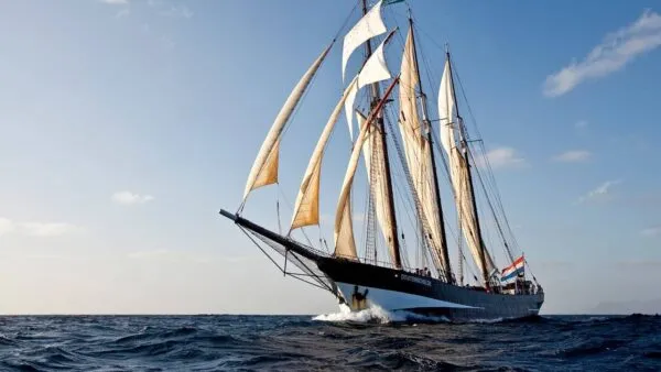 Het driemastzeilschip Oosterschelde vaart met gehesen zeilen over een diepblauwe oceaan bij Kaapverdië.